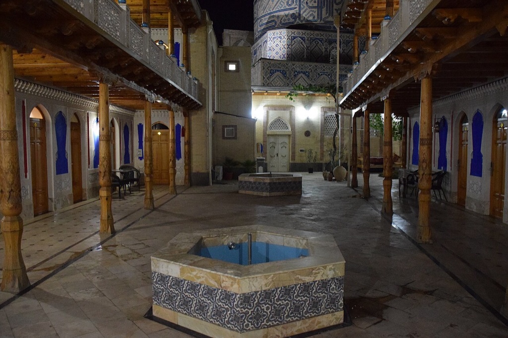 Carved wooden galleries around a tiled courtyard pool at a boutique hotel in Samarkand