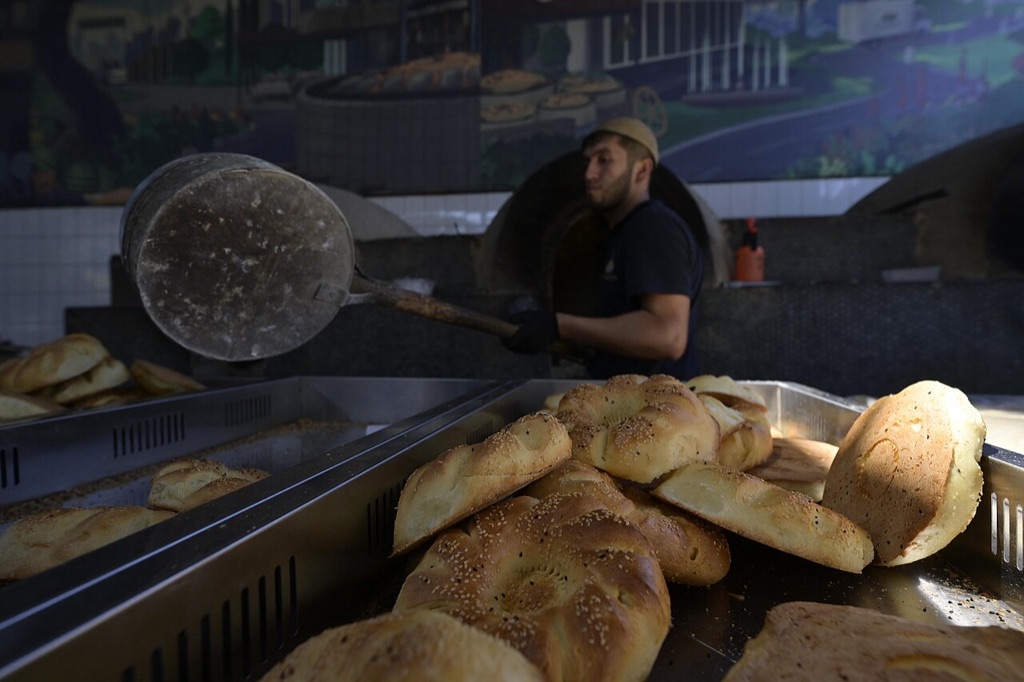 A baker lifting fresh non bread from a tandir oven in Uzbekistan